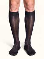 Front view of a man standing in NYLO 10D sheer black dress socks below the knee