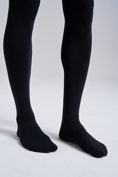Close-up of the lower legs and feet in NYLO 120D Opaque Tights in black, showing the fully footed legs.
