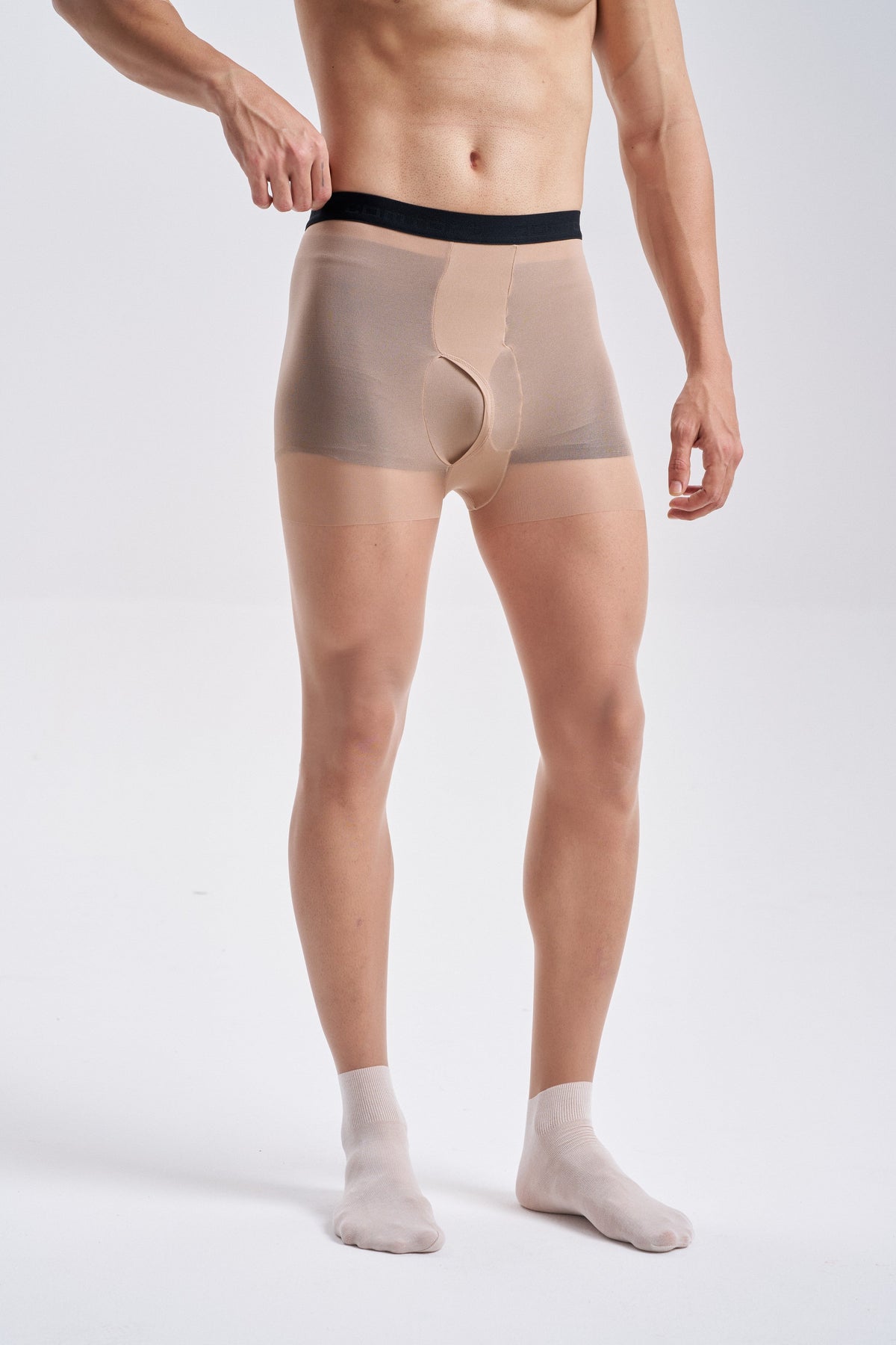 Front view of a man wearing NYLO 10D Sock Foot Sheer Tights in tan, waist to feet, with the white sock foot at the ankles and the black waistband.