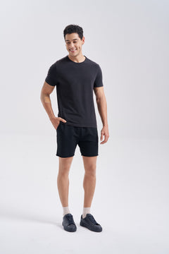 Man in a black t-shirt, black shorts and black sneakers wearing NYLO 10D Sock Foot Sheer Tights; his legs look bare and only a white ankle sock shows.