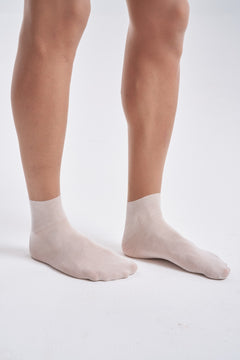 Close-up of the feet and lower legs in NYLO 10D Sock Foot Sheer Tights, showing the white sock foot joined to the tan sheer leg.